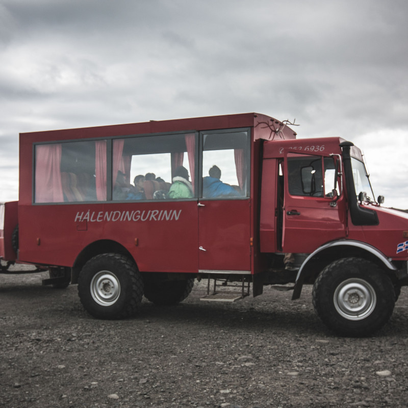 Ein roter LKW mit Touristen in der Kabine.