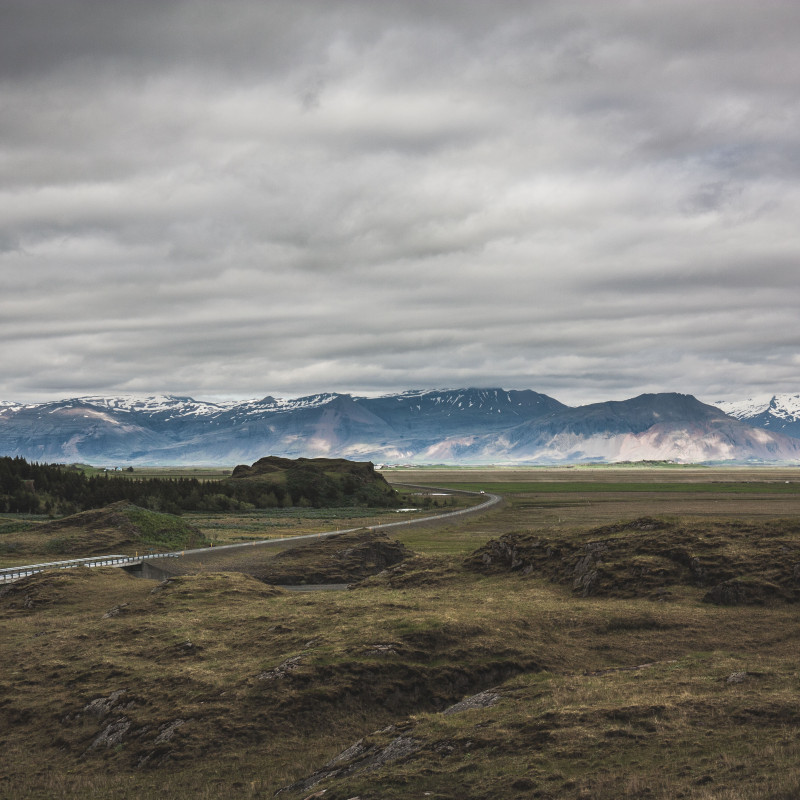 Die Straße schlängelt sich durch die Landschaft, im Hintergrund Gebirge.