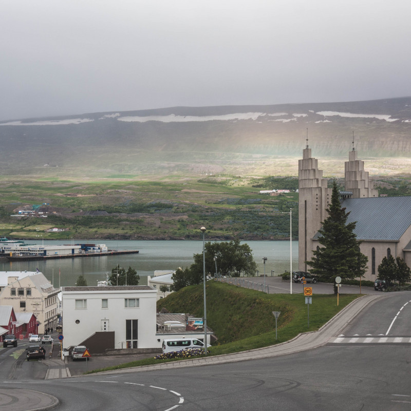 Blick den Berg hinunter: Kirche und Hafen und ein Regenbogen.