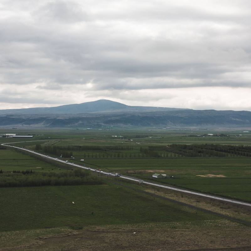 Weite Landschaft, die von einer Straße durchzogen wird.
