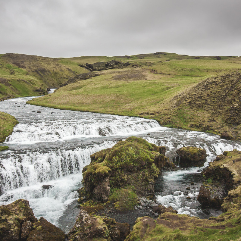 Mehrere kleinere Wasserfälle in eintöniger Landschaft.