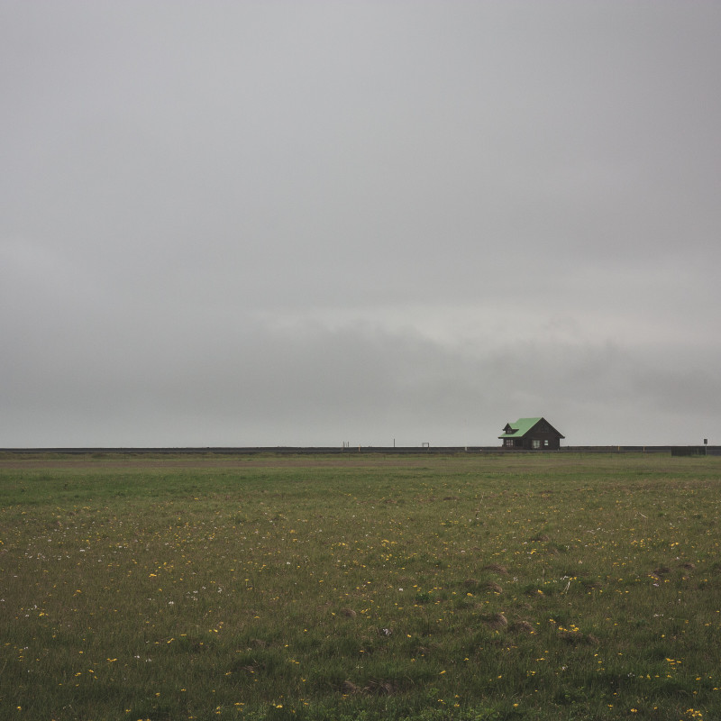 Ein Haus steht alleine in der weiten Landschaft.