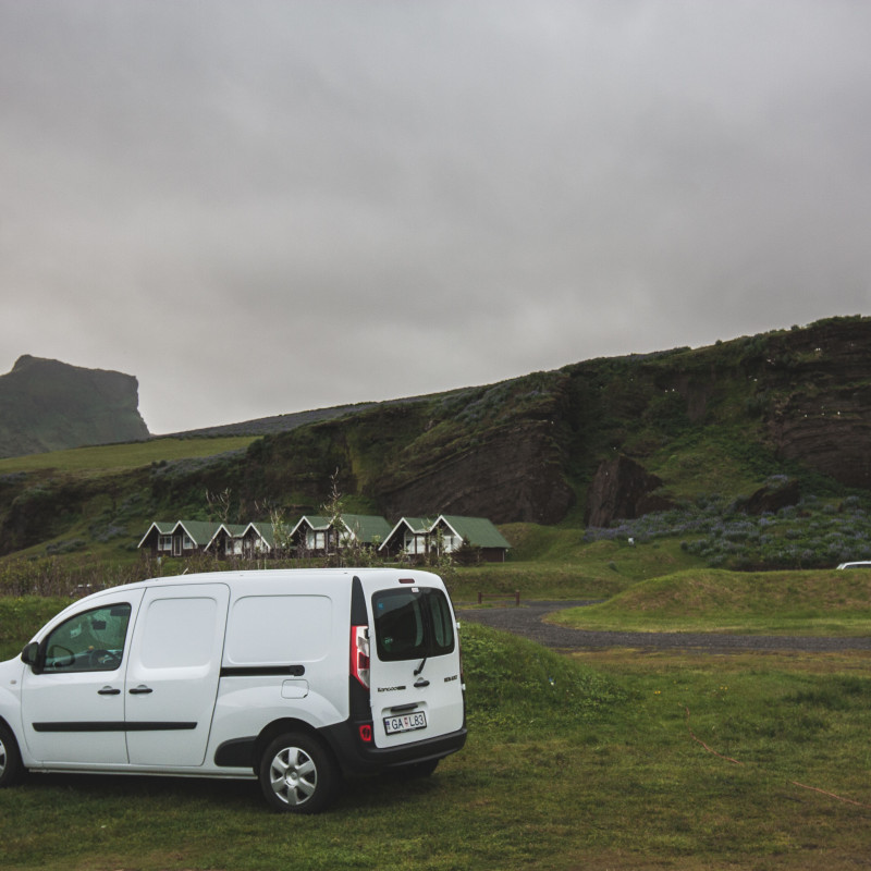 Ein Campervan auf dem Campingplatz. Im Hintergrund kleine Hütten.