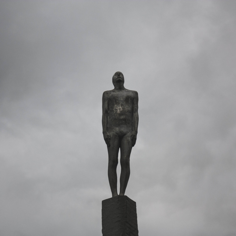 Eine Statue vor grauem Himmel.