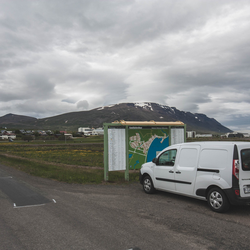 Campervan vor einer Informationstafel.