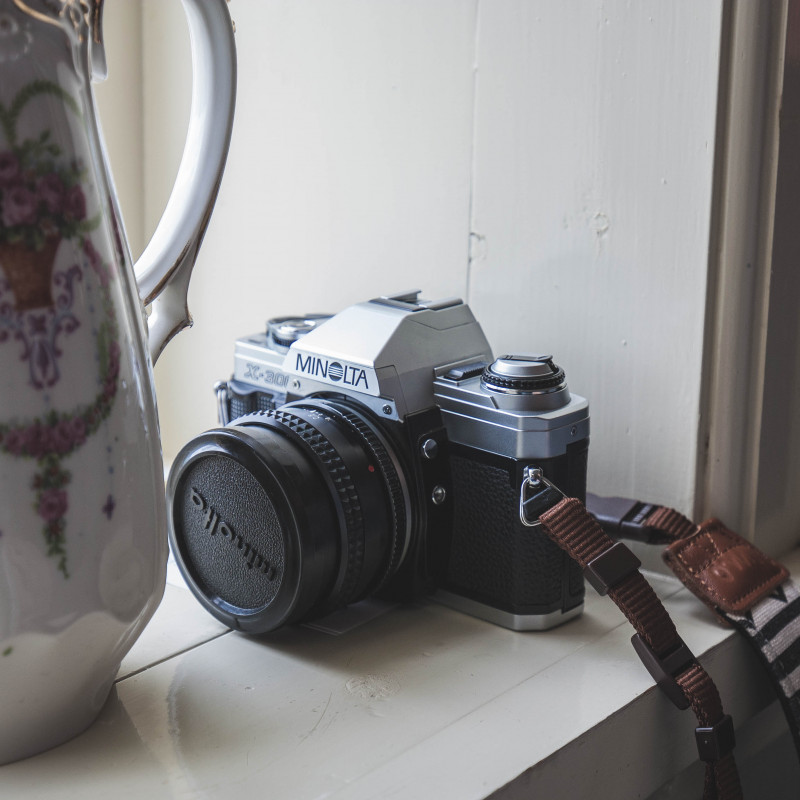 Eine alte Kamera neben einer Porzellankanne.