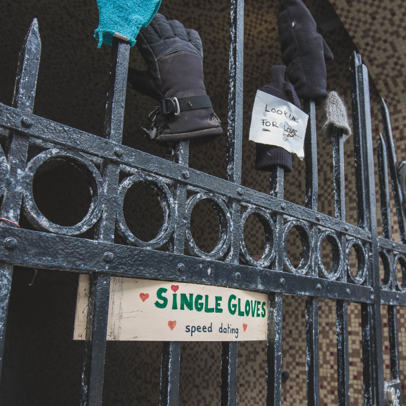 Einzelne Handschuhe stecken auf einem Zaun.