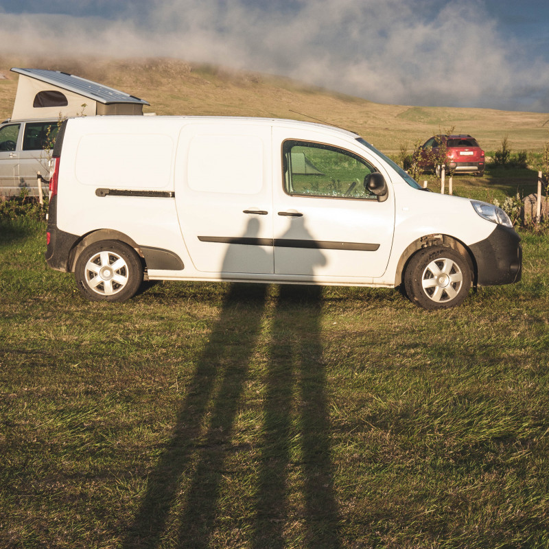 Lange Schatten zweiter Personen auf einem Campervan.