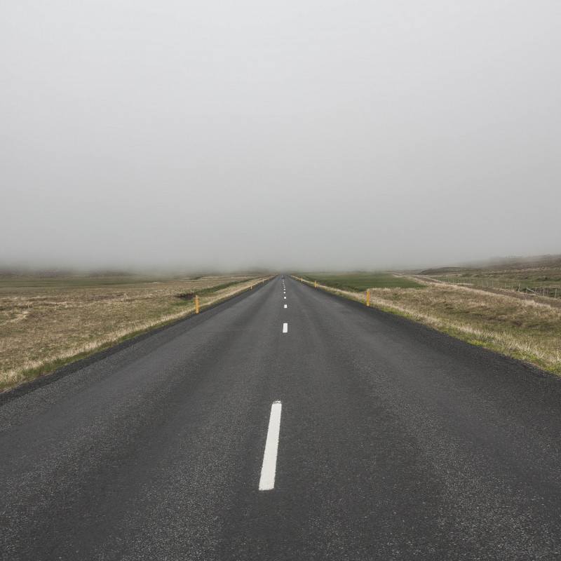 Eine Straße geht lange geradeaus und verschwindet am Horizont im Nebel.