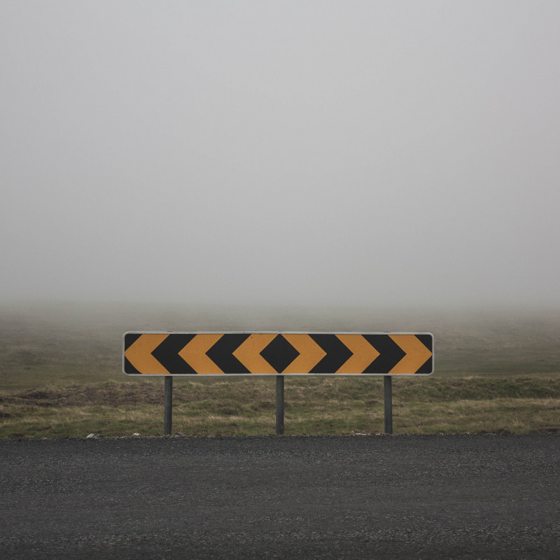 Eine Schild zur Straßenbegrenzung im Nebel.