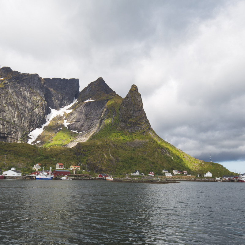 Boote und Häuser vor Bergen.