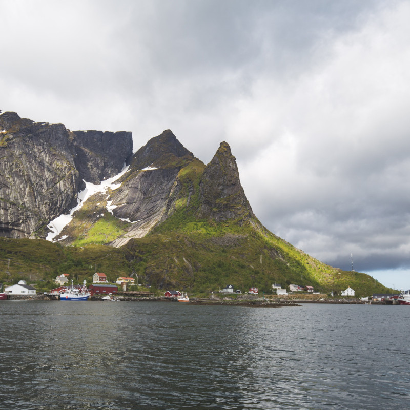 Boote und Häuser vor Bergen.