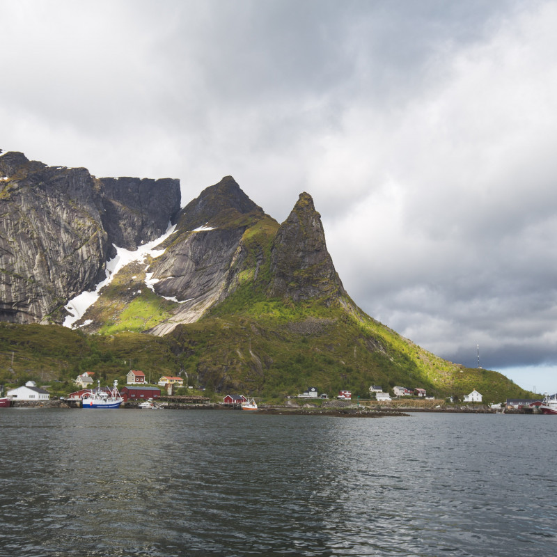 Boote und Häuser vor Bergen.