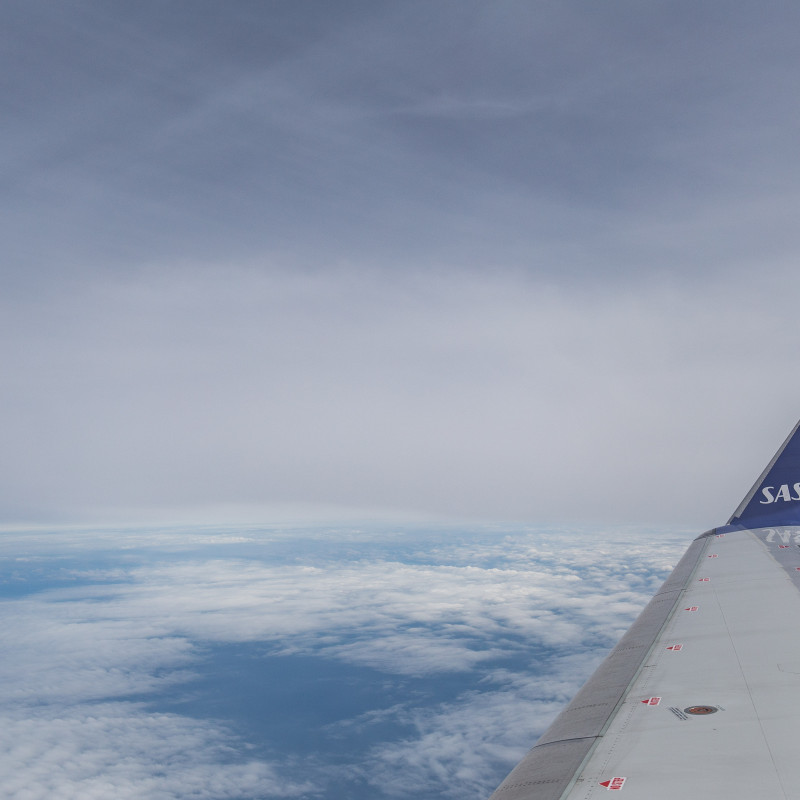 Ein Flugzeugflügel der Fluggesellschaft SAS über den Wolken.