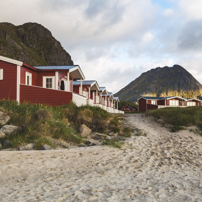 Rote Häuser am Strand, Berge im Hintergrund.
