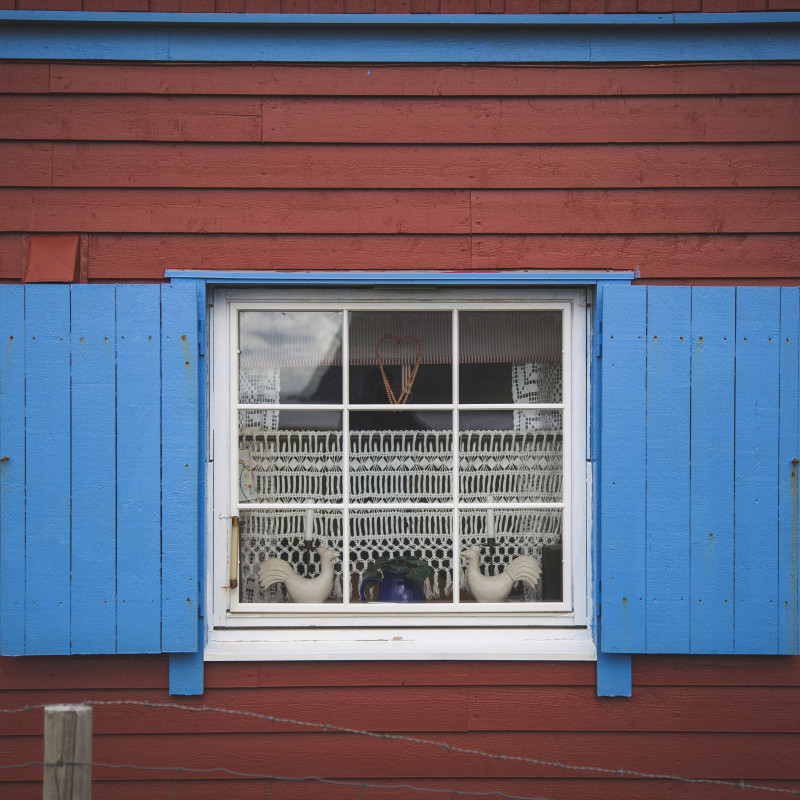 Blaues Fenster an rotem Haus.
