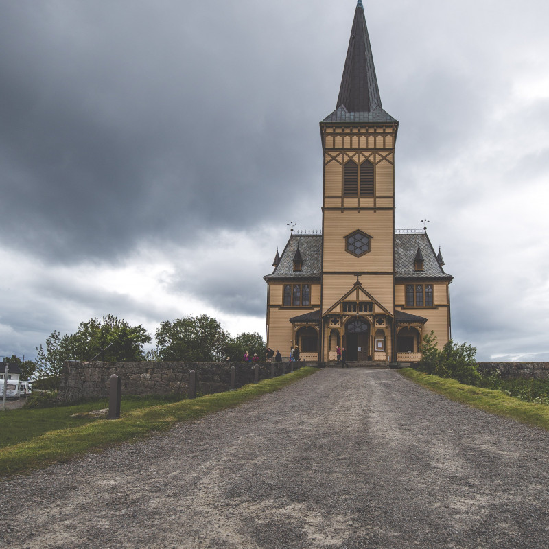 Eine Kirche aus Holz vor grauem Himmel.