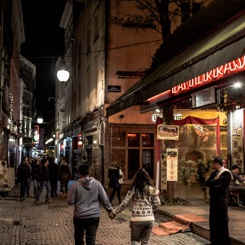 Zwei Menschen laufen im dunkeln Hand in Hand durch die Brüsseler Innenstadt.