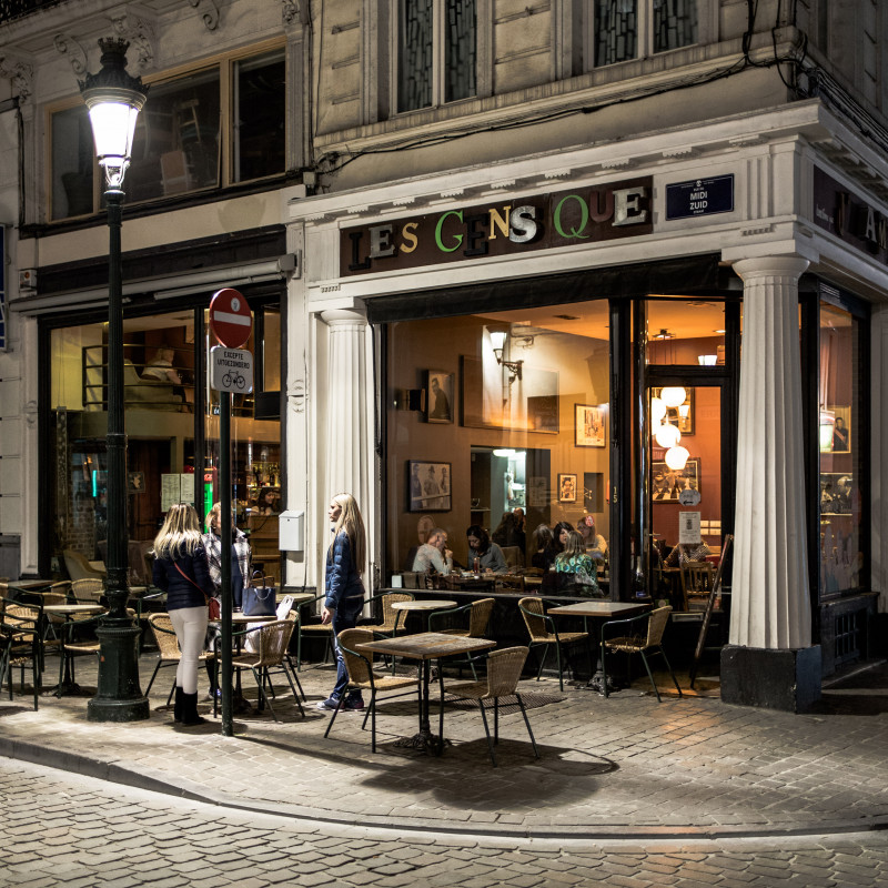 Zwei Frauen stehen am Abend rauchend vor einem Café in der Brüsseler Innenstadt.