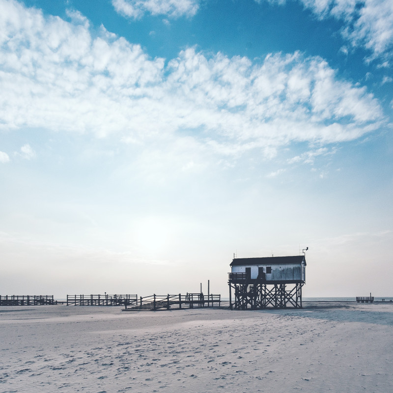 Strand von St. Peter-Ording. Im Hintergrund ein Haus auf Stelzen.