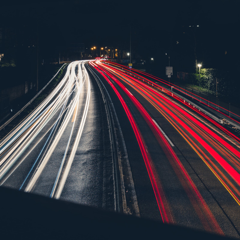 Autos hinterlassen Lichtspuren in der Dunkelheit.