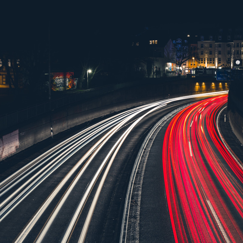 Autos hinterlassen Lichtspuren in der Dunkelheit.