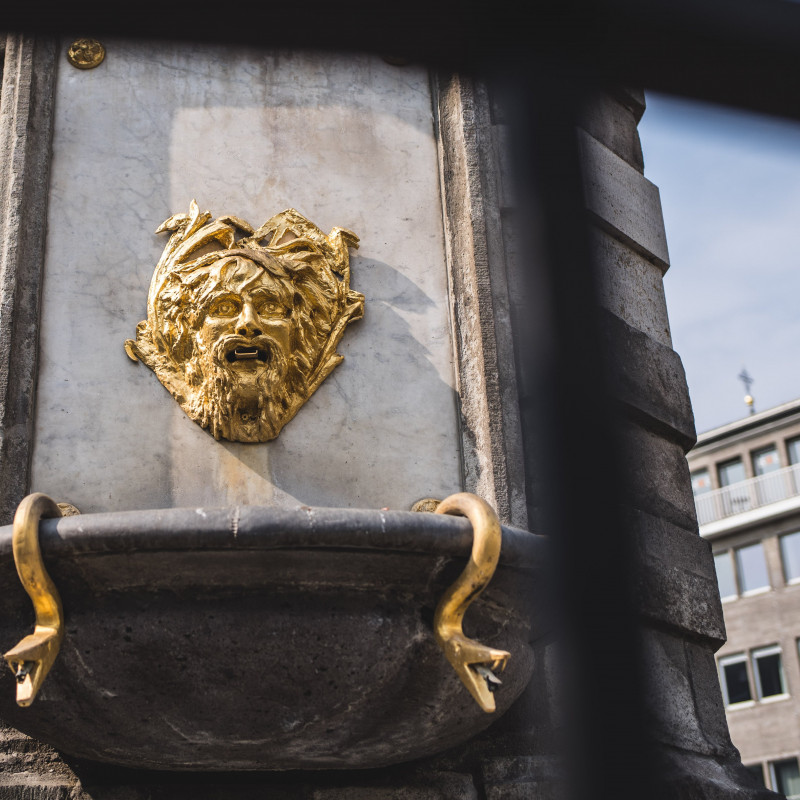 Ein goldener Kopf an einem Brunnen.