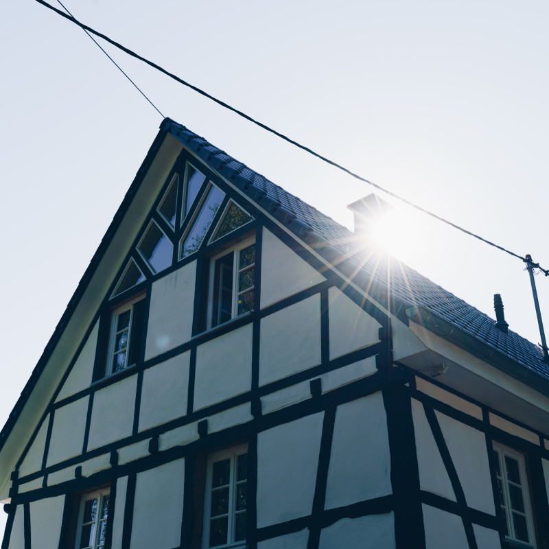 Die Sonne strahlt über dem Dach eines Hauses.