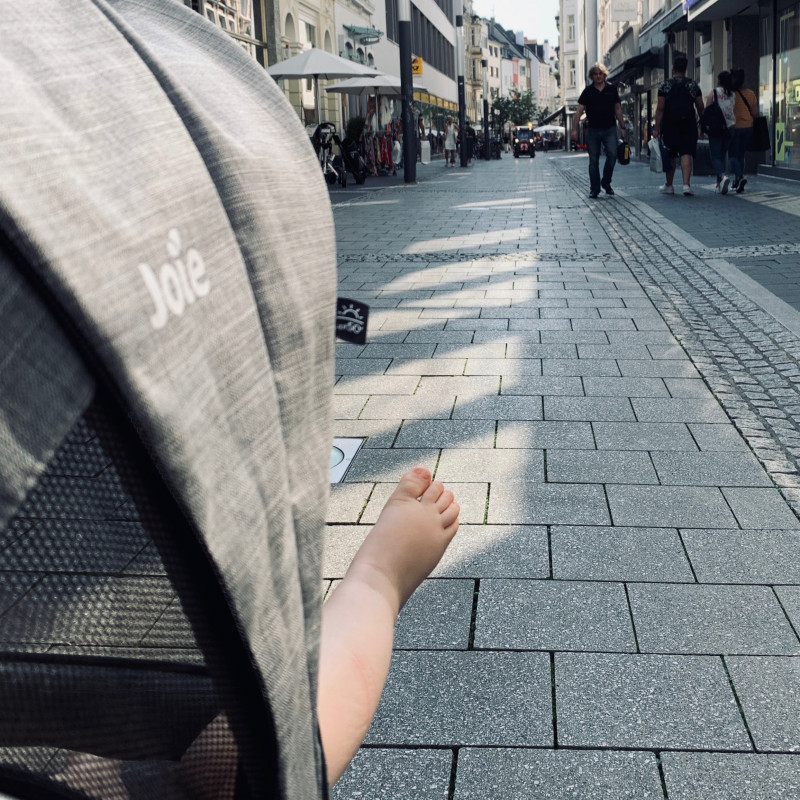 Ein kleiner Kinderfuß hängt aus dem Kinderwagen heraus.