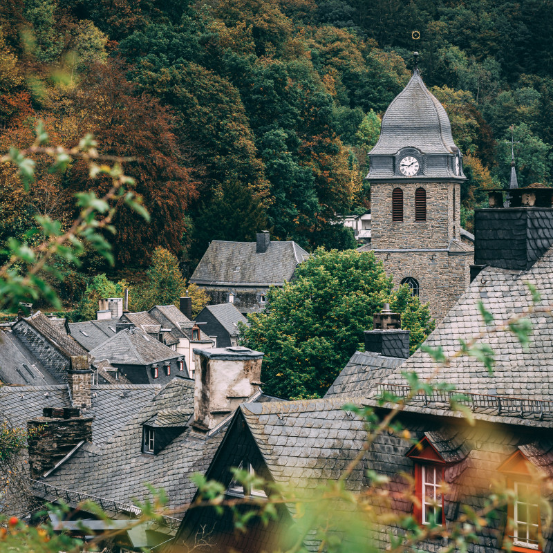 Ein Kirchturm ragt zwischen Dächern empor.