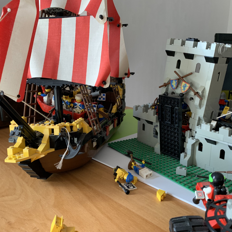 Ein LEGO-Piratenschiff und eine Ritterburg stehen staubig und schief auf einem Tisch.