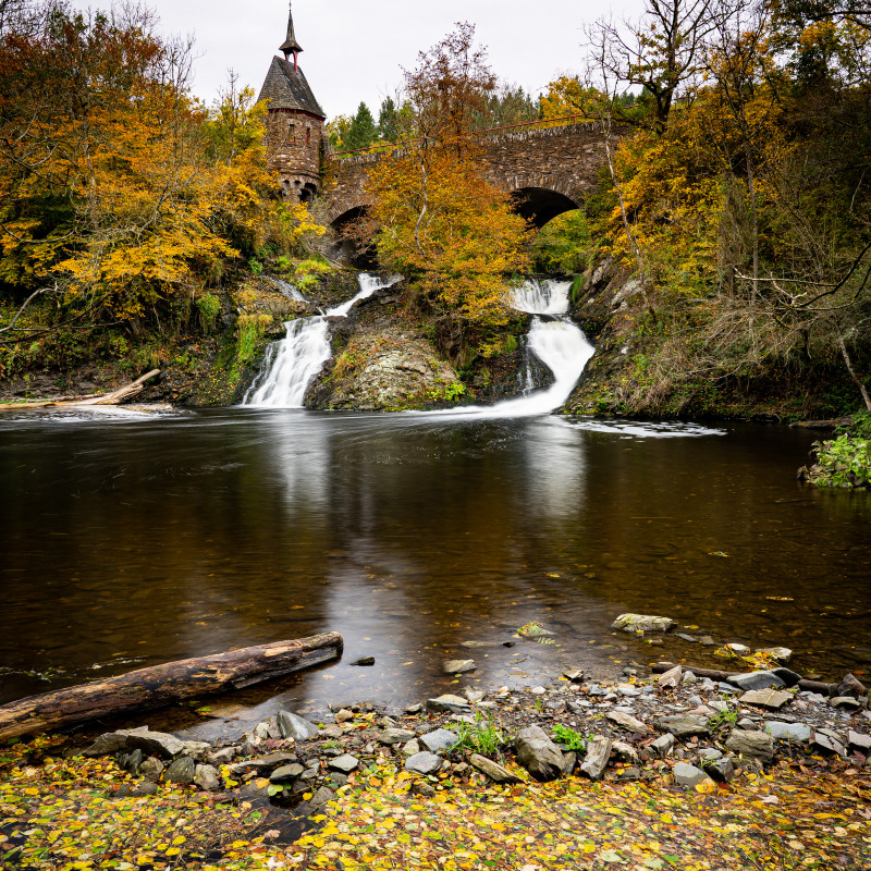 Ein Wasserfall unter einer Brücke.