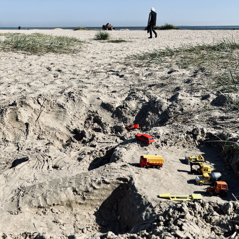 Spielzeug-Fahrzeuge im Sand.