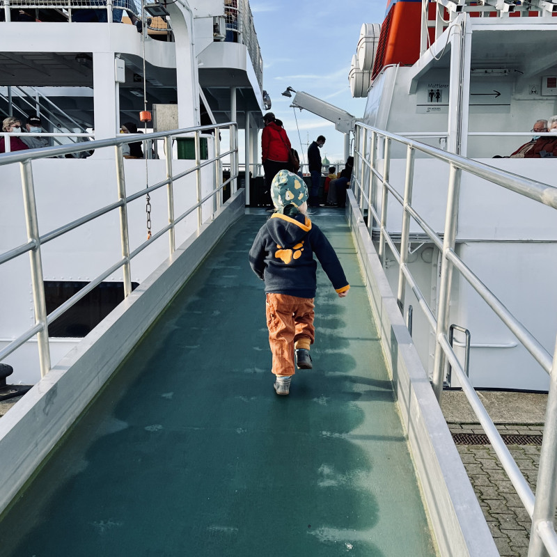Ein Kind läuft über eine Brücke auf ein Schiff.