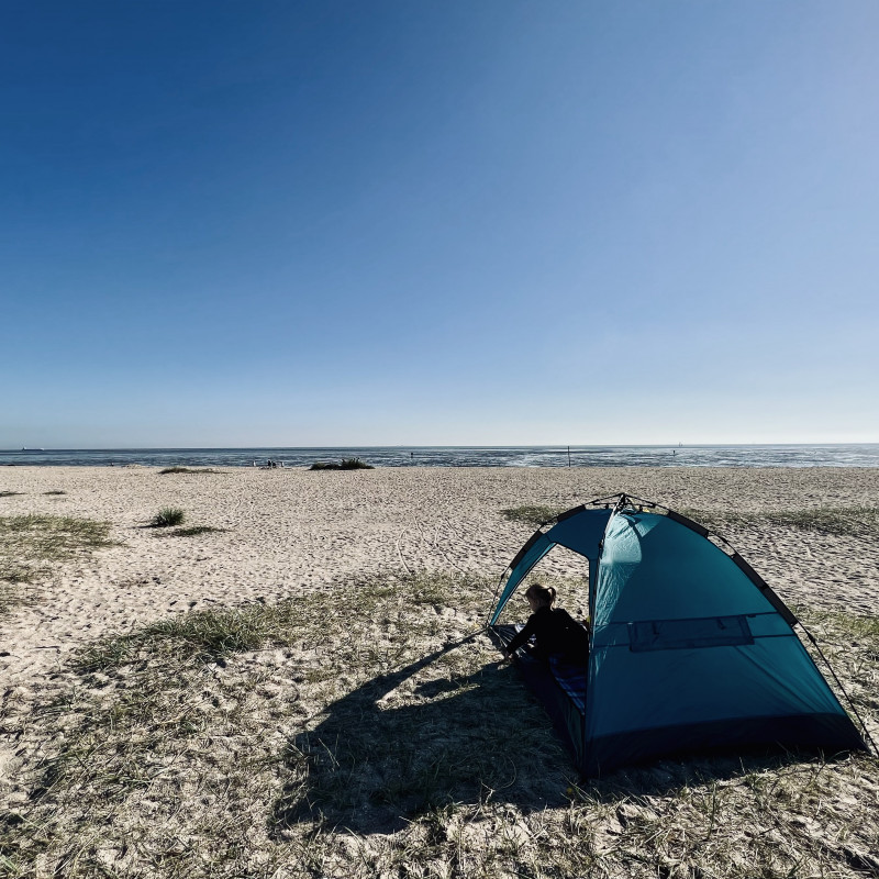 Ein Zelt auf einem Sandstrand.