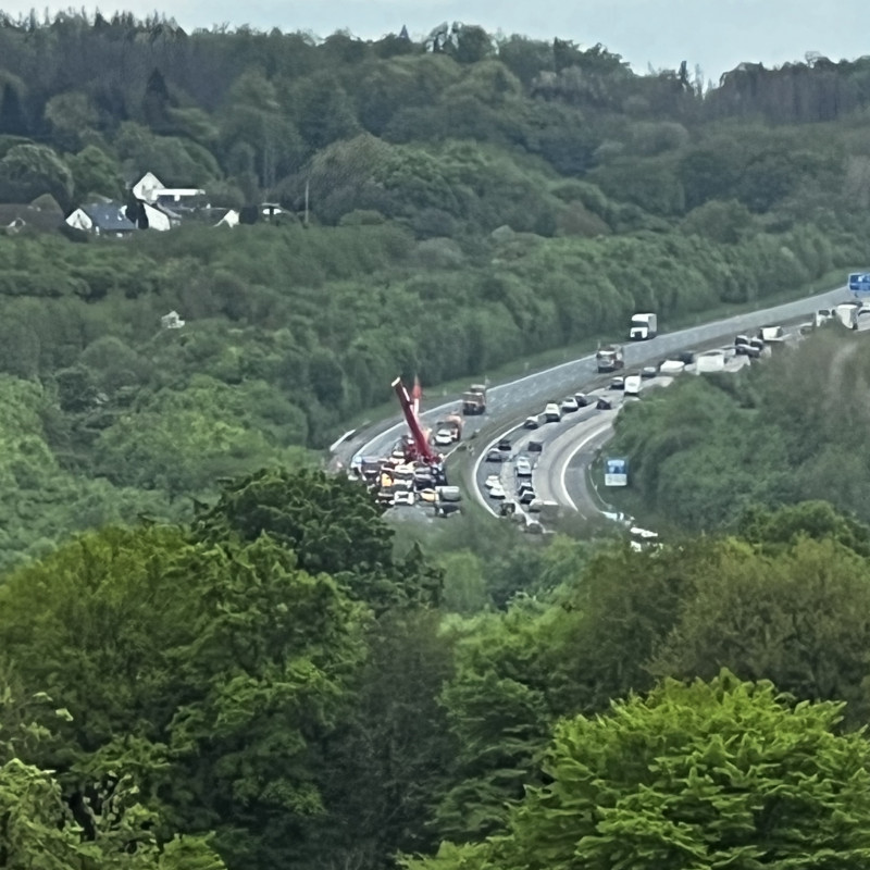 Ein verschwommenes Bild einer fernen Autobahn auf der zwei Kräne gerade einen LKW aufrichten.