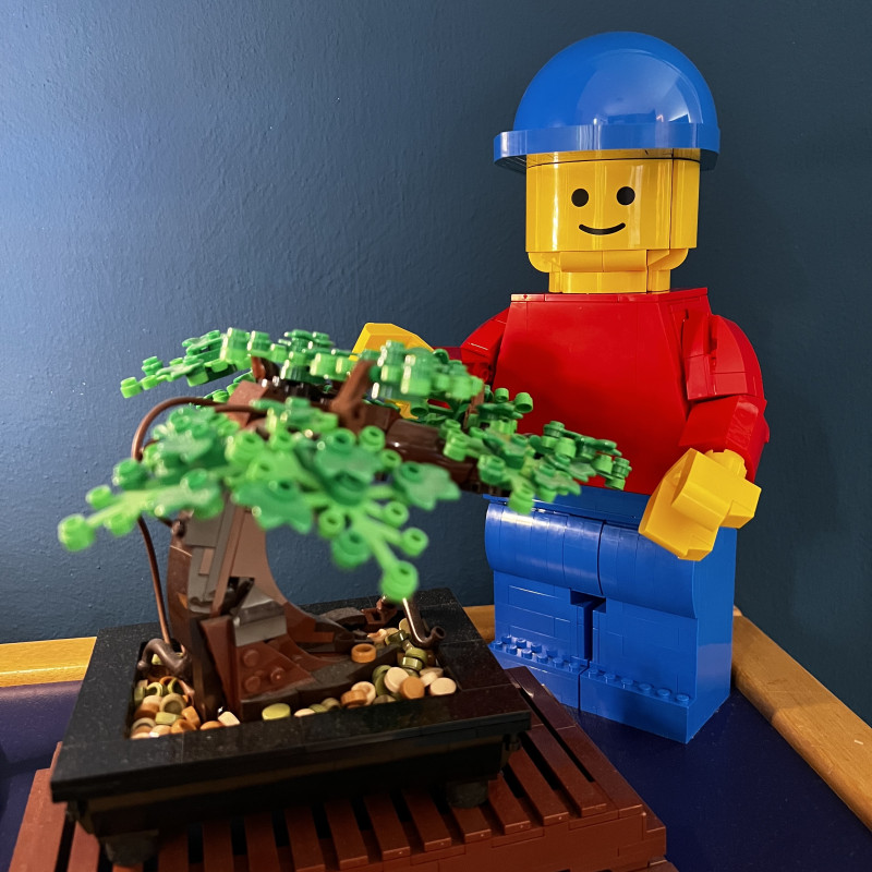 Eine große, aus Lego-Steinen gebaute Lego-Figur steht hinter einem aus Lego-Steinen gebauten Baum.