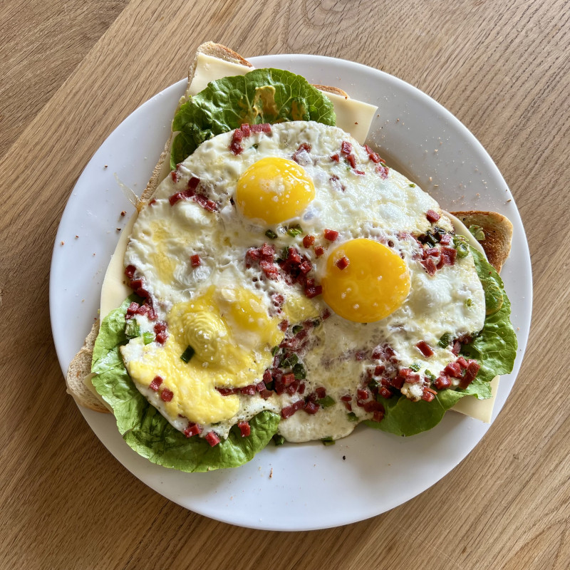 Drei Spiegeleier mit Speck auf Toast.