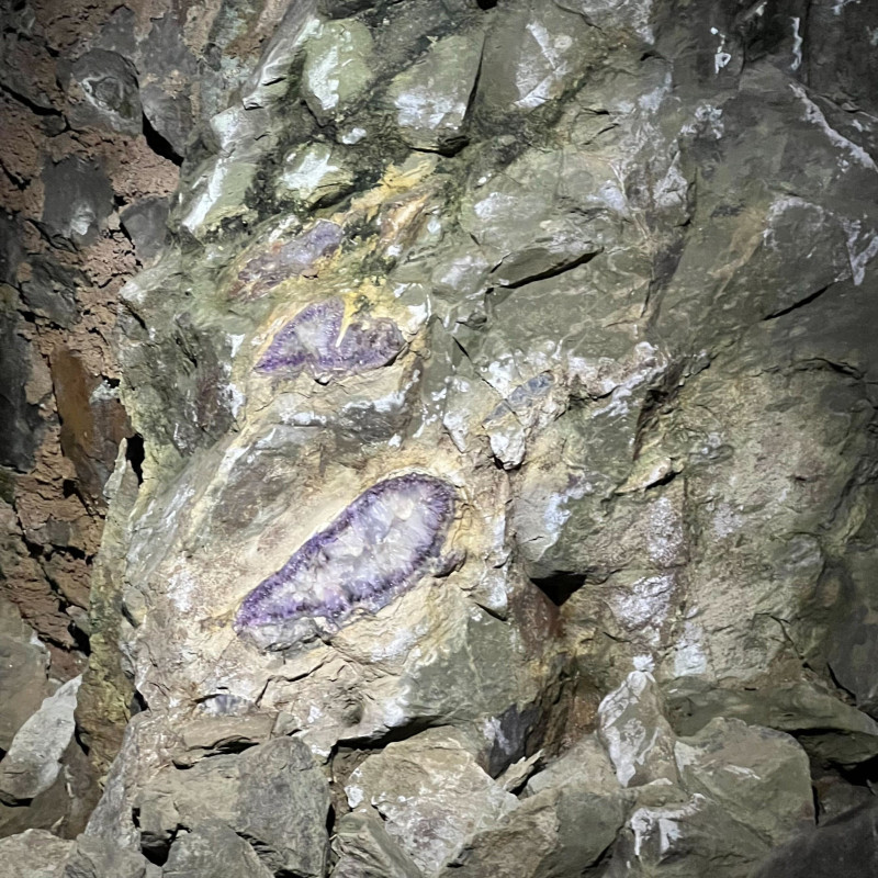 Violett-weiße Edelsteine in grauem Felsen.
